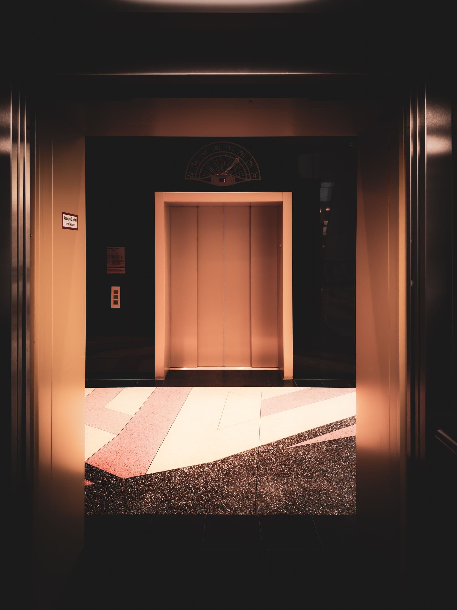 Lift doors at the end of a dimly lit lobby